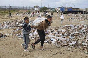 File - A Palestinian boy carries water looted from the humanitarian aid trucks during the ongoing Israeli bombardment of the Gaza Strip at the border with Egypt in Rafah on Monday, Nov. 20, 2023.