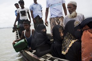 Myanmar's Rohingya ethnic minority use a local boat to cross a stream after crossing over to the Bangladesh side of the border near Cox's Bazar's Dakhinpara area, Saturday, Sept. 2, 2017.