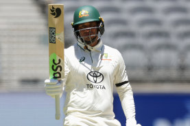 Khawaja raises the bat after reaching his half-century.