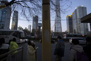 A commuter wearing a face masks checks a schedule at a bus shelter during the evening rush hour in the central business district in Beijing, China