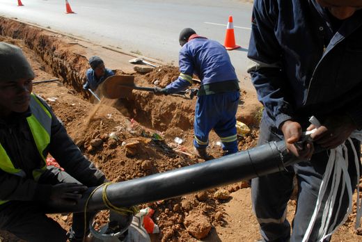 Workers replace a stolen electric cable in the Soweto township.