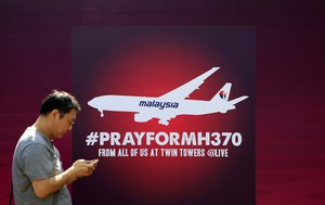 A man walks past a board reading "Pray for MH370" for passengers aboard a missing Malaysia Airlines plane, in Kuala Lumpur, Malaysia