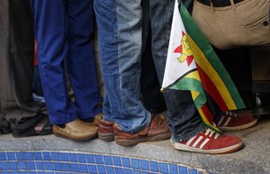 Supporters of Zimbabwe's President in waiting Emmerson Mnangagwa, one carrying a national flag, stand on top of a fountain as they await his arrival at the Zanu-PF party headquarters in Harare, Zimbabwe Wednesday, Nov. 22, 2017.