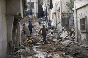 Palestinians walk through the aftermath of the Israeli military raid on Nur Shams refugee camp in the West Bank, Wednesday, Dec. 27, 2023. Israel's forces raided a refugee camp in the northern occupied West Bank, killing at least six Palestinians, Palestinian health authorities said early Wednesday.