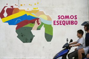 A boy drives a motorcycle in front of a mural of the Venezuelan map with the Essequibo territory included in the 23 de Enero neighborhood of Caracas, Venezuela, Monday, Dec. 11, 2023.