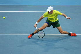 Alex de Minaur races across court.