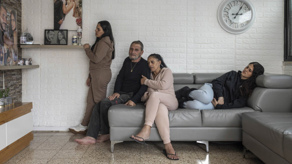 Gal Abdush’s parents, center, and her sisters at their home in Kiryat Ekron, a small town in central Israel, Dec. 7, 2023. The photograph on the wall shows Gal and her husband, Nagi — they had been together since they were teenagers. (Avishag Shaar-Yashuv/The New York Times)