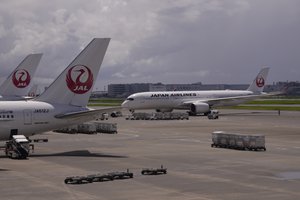 Japan Airlines airplanes are parked at a terminal as another prepares to take off from the Haneda international airport in Tokyo, Wednesday, Aug. 23, 2023