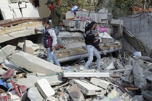 Palestinians evacuate a child from the rubble of the Darwesh family building destroyed in an Israeli airstrike in Nusseirat refugee camp, central Gaza Strip, Tuesday, Jan. 2, 2024