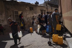 FILE - Palestinians collect water from a water tap, amid drinking water shortages, in Khan Younis, Gaza Strip, Sunday, Oct, 15, 2023. Since the Israeli military decided to cut off the Gaza Strip's water and fuel and prevent aid convoys from entering, Palestinians in Gaza have sheltered with their families far from their homes and struggled to survive. It's a grueling routine — waiting hours for bread, trying to find water, soothing children during bombings.