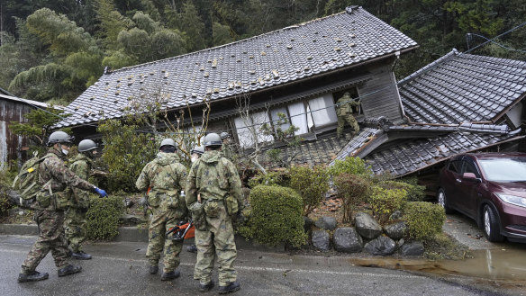 Japanese Self Defence Force members inspect a collapsed house hit by earthquakes in Suzu, Ishikawa.