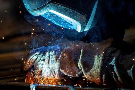 A variety of colors reflect in a welder's mask as he works.