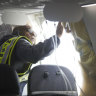 A National Transportation Safety Board  investigator examining the fuselage plug area of Alaska Airlines Flight 1282.