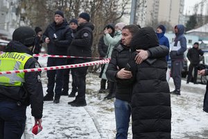 People react at the site of a Russian attack in Kyiv, Ukraine, Tuesday, Jan. 23, 2024.