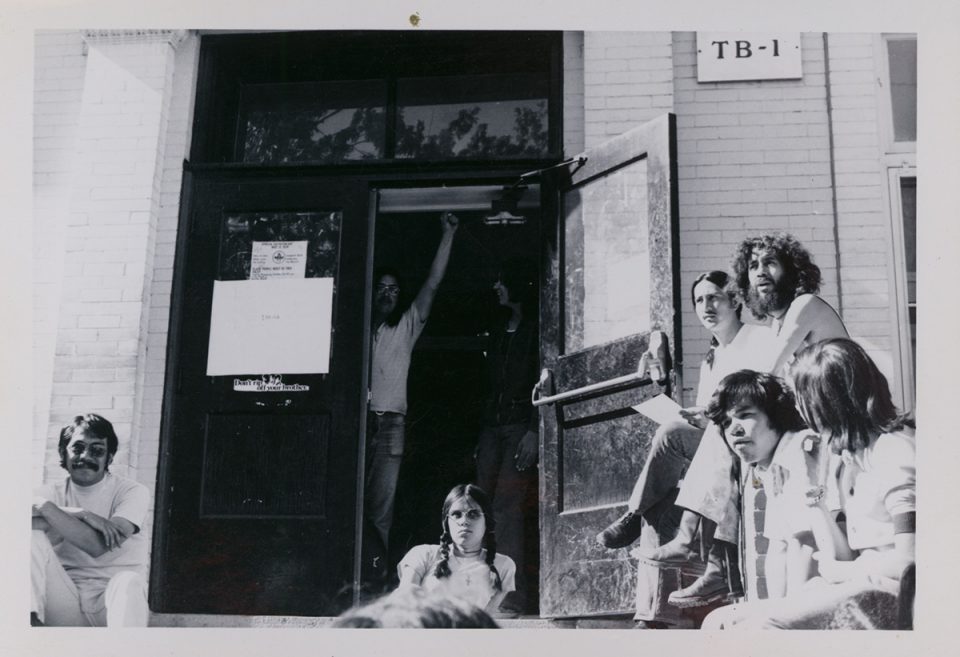 Picture of students standing and sitting outside of TB-1