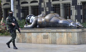 File - A police officer wearing a mask amid the spread of the new coronavirus, patrols near a sculpture by Colombian artist Fernando Botero during the "I take care of Medellin" campaign in Medellin, Colombia, June 9, 2020.