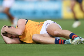 Adelaide’s Mark Keane holds his head after being concussed by Port’s Sam Powell-Pepper.