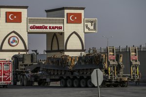 A Turkish forces truck transporting armoured personnel carriers, crosses the border with Syria in Karkamis, Gaziantep province, southeastern Turkey, Tuesday, Oct. 15, 2019.