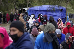 FILE - Migrants from Venezuela line up in the cold weather for hot drinks and food from volunteers at a makeshift camp on the U.S.-Mexico Border in Matamoros, Mexico, Dec. 23, 2022. The Supreme Court is keeping pandemic-era limits on people seeking asylum in place indefinitely, dashing hopes of immigration advocates who had been anticipating their end this week. The restrictions, often referred to as Title 42, were put in place under then-President Donald Trump at the beginning of the pandemic to curb the spread of COVID-19. (AP Photo/Fernando Llano, File)