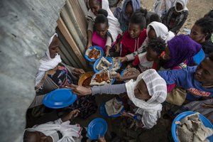 In this Sunday, May 9, 2021 file photo, displaced Tigrayans line up to receive food donated by local residents at a reception center for the internally displaced in Mekele, in the Tigray region of northern Ethiopia.