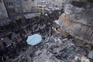 Palestinians shop at a local market next to a destroyed residential building by the Israeli airstrikes, during the Muslim holy month of Ramadan, in Rafah, Gaza Strip, Thursday, March 14, 2024.