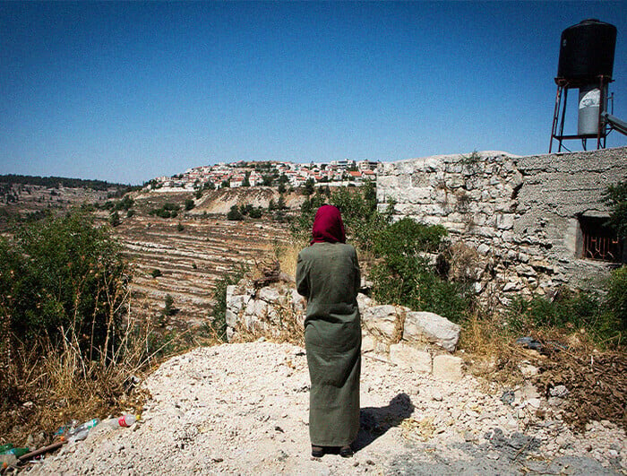 A woman stands overlooking illegal Israeli settlements in the West Bank.