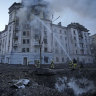 Firefighters work near the crater at the site after Russian attacks in Kyiv, Ukraine, on Thursday.