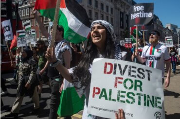 A protester holds a "Divest for Palestine" sign during a march in London, England on May 14, 2022. (Photo: Getty Images)