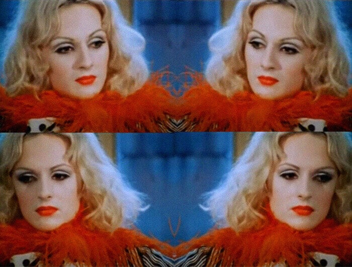 Four stills of Candy Darling in Flesh. She appears with red lipstick and in a red feather boa.