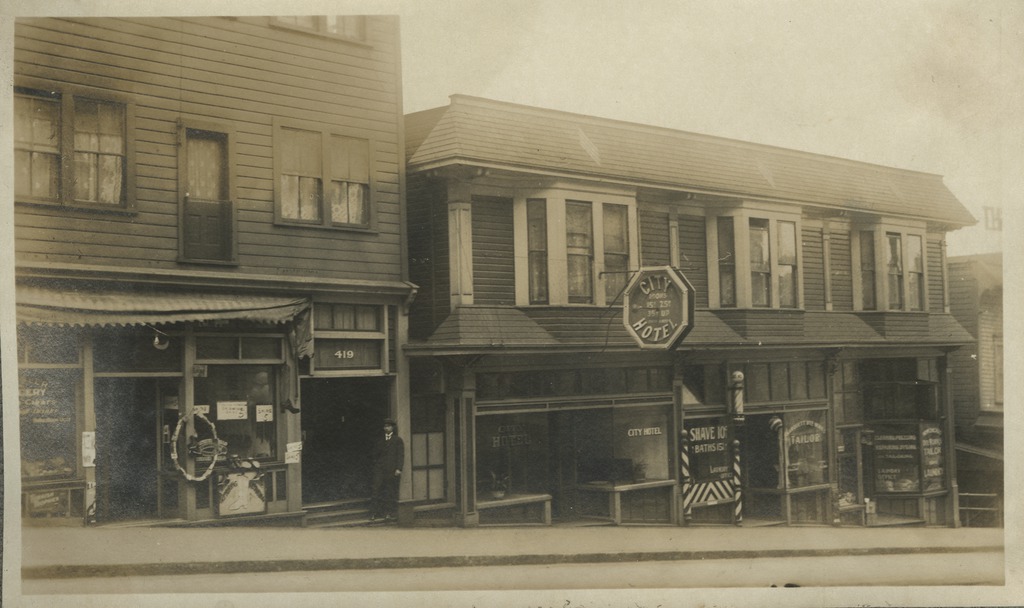 A man stands in the doorway of his hotel, located on Yesler Avenue in Seattle's Nihonmachi or Japantown, circa 1913.