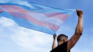 A man holds up a transgender flag.