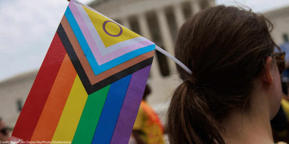 Someone holding an LGBTQ+ flag.