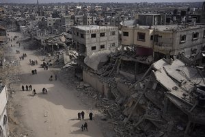 Palestinians walk through the destruction in the wake of an Israeli air and ground offensive in Khan Younis, southern Gaza Strip, Monday, April 8, 2024. Israel says it has withdrawn its last ground troops from the city, ending a four-month operation.