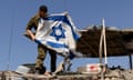 A soldier hangs an Israeli flag on an armoured personnel carrier near the border with Gaza