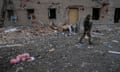 A Ukrainian serviceman walks past damaged buildings.