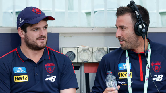 Angus Brayshaw, left, joins Melbourne official Marcus Wagner on the interchange bench.