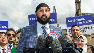 Leader of the Workers Party of Britain George Galloway (right) looks on as former England cricketer Monty Panesar (centre) addresses fellow party candidates in Parliament Square.