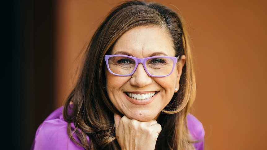 Portrait of Anita Heiss, who is wearing glasses with her chin resting on her fist