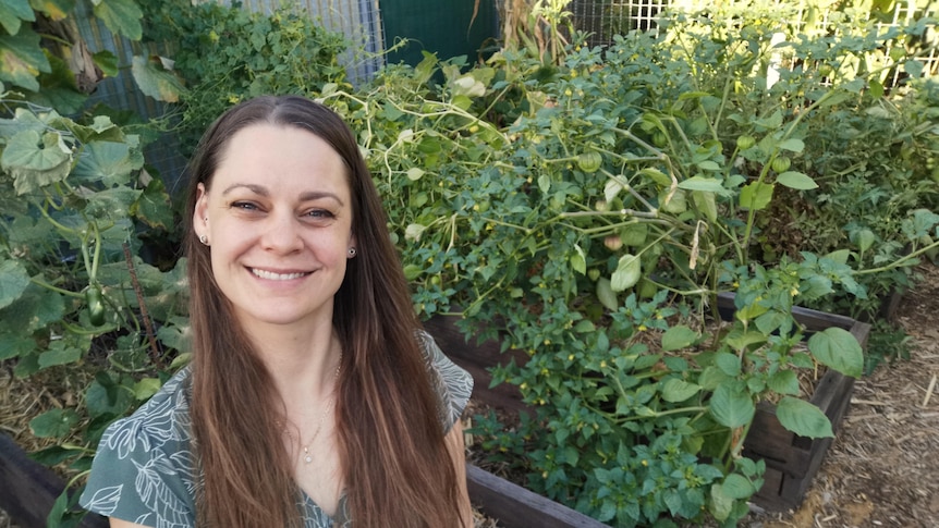 Koren Helbig in her garden, with plenty of summer veggies growing in raised garden beds she filled using hügelkultur.