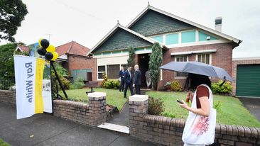 Someone with an umbrella walks past an auction.