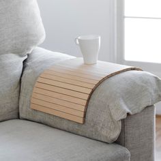 a coffee cup sitting on top of a wooden table next to a gray couch in a living room