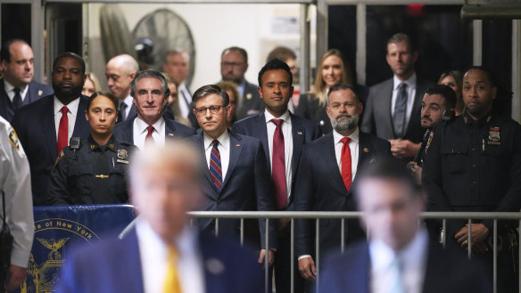 From left, North Dakota Gov. Doug Burgum, U.S. Speaker of the House Mike Johnson and businessman Vivek Ramaswamy  look on as former President Donald Trump talks to the media outside Manhattan criminal court in New York