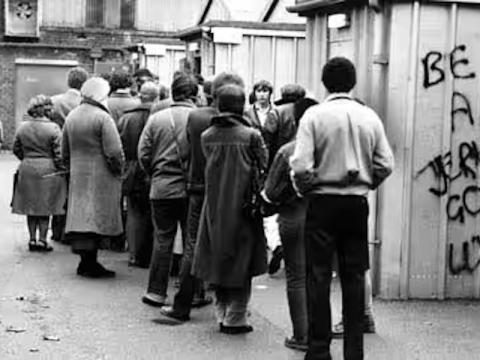 Queue of people including grafitti "Be A Jerk Go To Work"