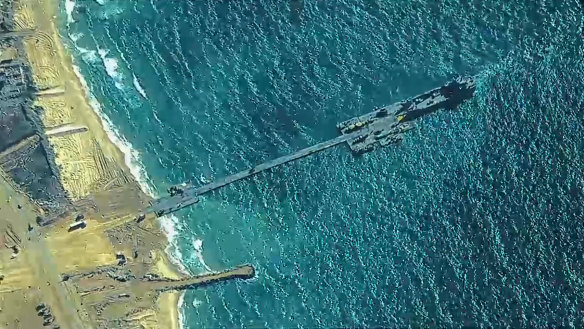 US forces Army soldiers  and US Navy  assigned to Amphibious Construction Battalion 1, and Israel Defense Forces emplace the Trident Pier, May 16, 2024 on the Gaza coast. The temporary pier, part of the Joint Logistics Over-the-Shore capability, will enable the maritime delivery of international humanitarian aid to the United Nations in Gaza for distribution to Palestinian people in need. (Photo by U.S. Central Command via Getty Images)