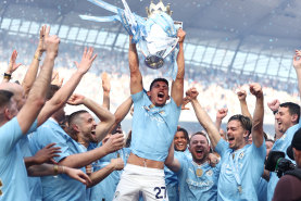 Matheus Nunes holds the Premier League trophy aloft as Manchester City celebrate their title victory.