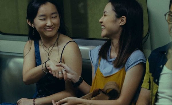 Two women on a train smile and shake hands