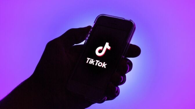 A TikTok logo displayed on a smartphone with a purple background.