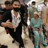 Keith Davis, centre, is whisked away, prevented from talking to reporters at Samitivej Srinakarin Hospital in Bangkok, Thailand, on Thursday.