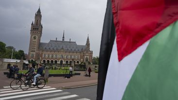 A lone demonstrator waves the Palestinian flag outside the Peace Palace, rear, housing the International Court of Justice, or World Court, in The Hague, Netherlands, Friday, May 24, 2024.  