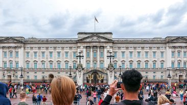 London, UK - 10th October 2023: Tourist taking picture of the majestic and iconic Buckingham Palace in London, royal residence of the King and Queen of the United Kingdom, crowd of tourists outside